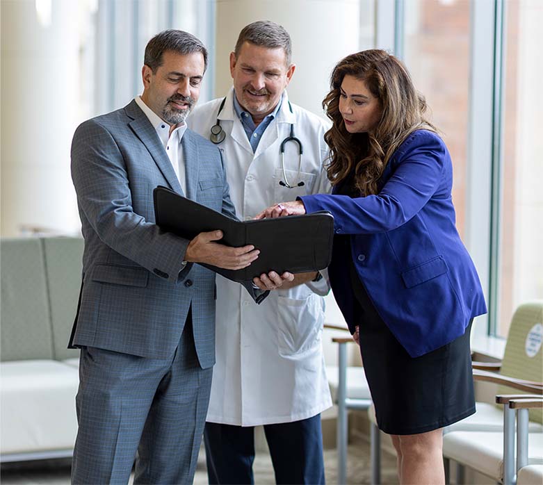 Three Doctors all looking at the same document on a tablet.