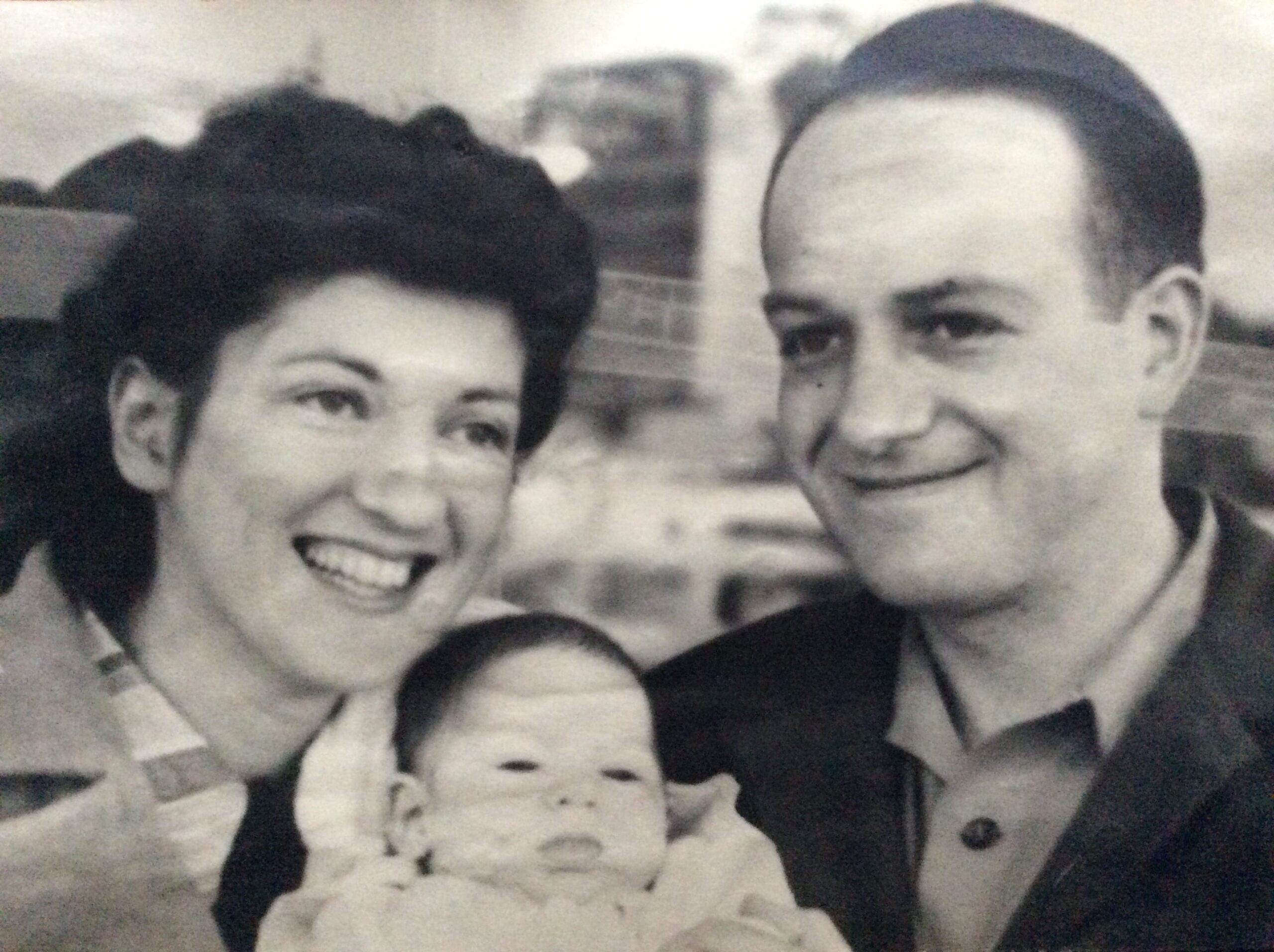 A smiling Dr. Morris Collen and his wife holding their newborn child.